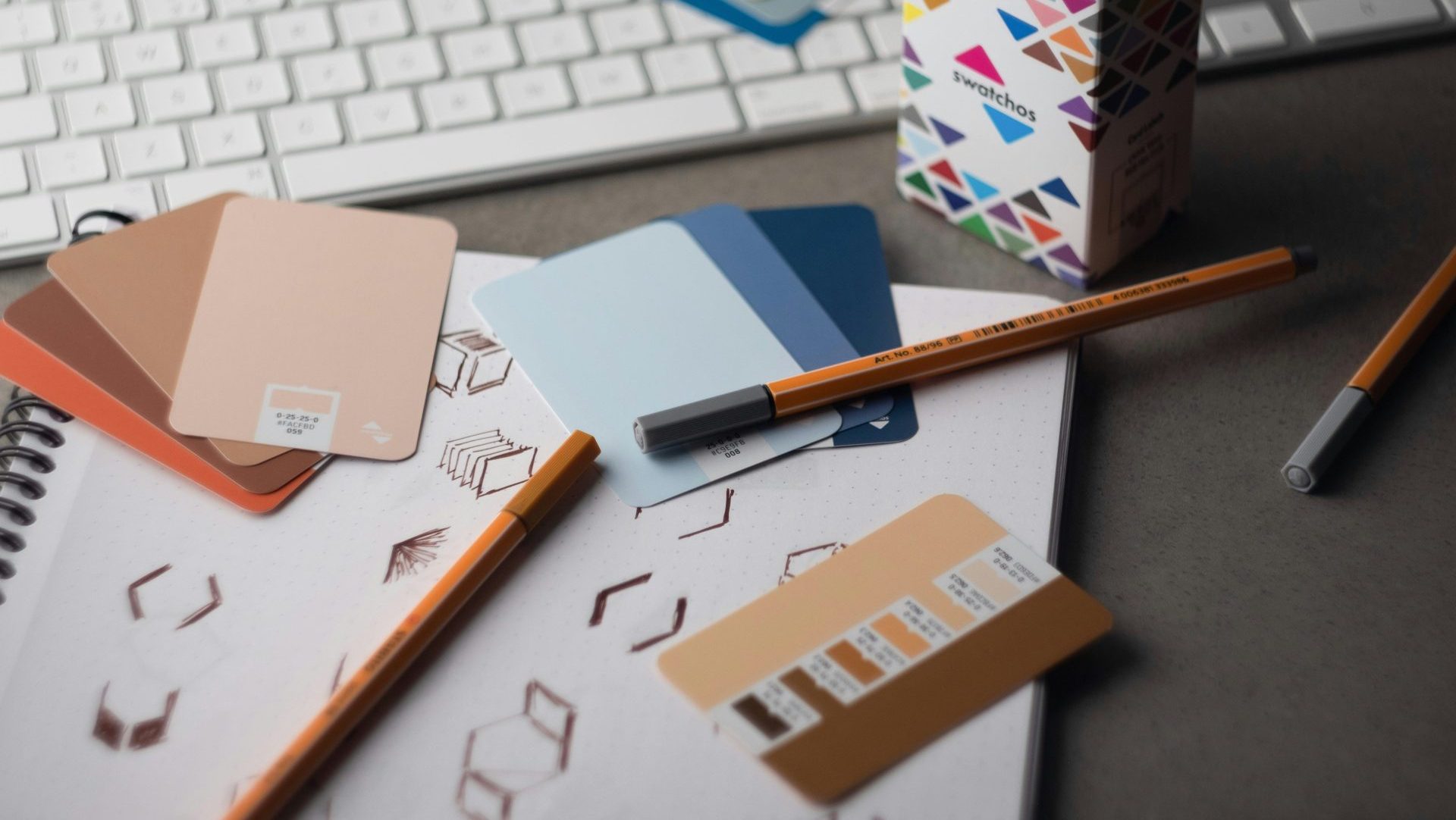 a desk with a keyboard, pencils, and various color samples