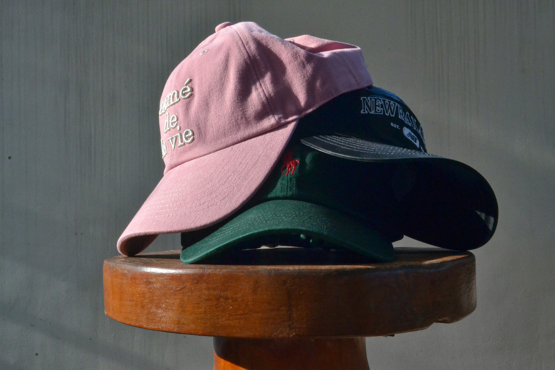 Three baseball caps stacked on a stool
